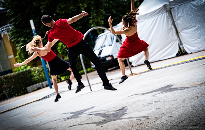 Trois danseurs en rouge et noir dansent devant l’arrêt de métro Fort d’Aubervilliers pendant l’AuberJazz Day