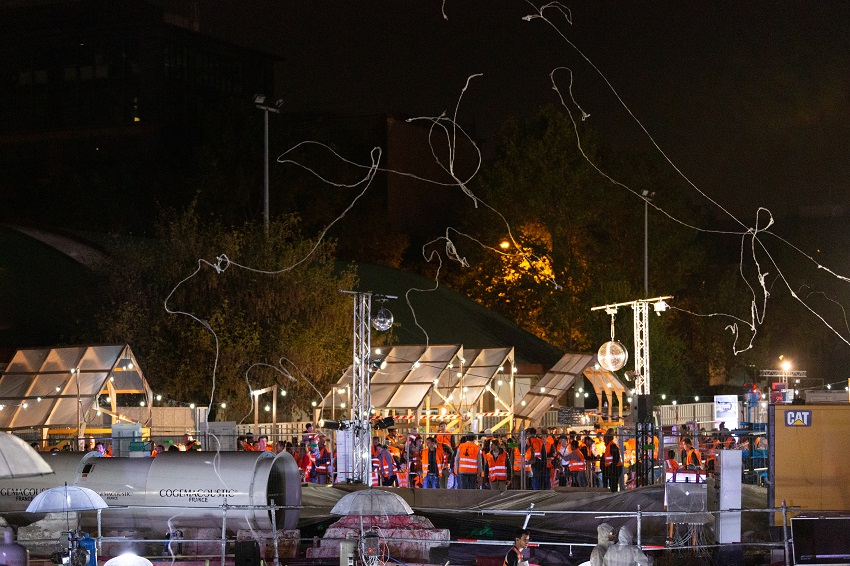 Filaments de sucre au-dessus du public du KM7 en gilets oranges de chantier, de nuit sur le chantier du Puits Mandela à Saint-Denis 