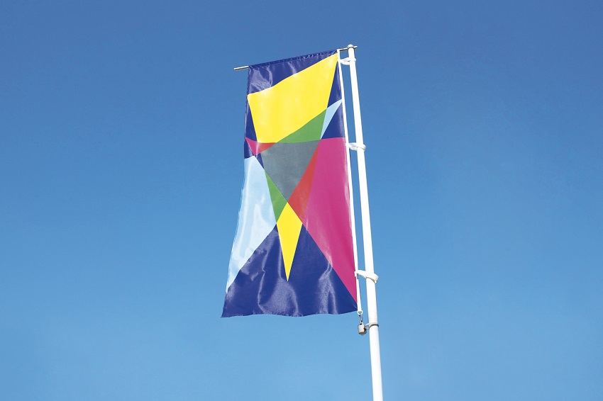 Drapeau avec motifs triangulaires jaunes, roses, bleux, dans le cadre du chantier du partagé « Agrafmobile » par Malte Martin à La Courneuve en 2018