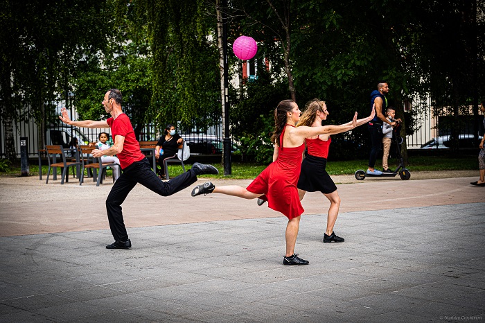 Trois danseurs en rouge et noir dansent devant l’arrêt de métro Fort d’Aubervilliers pendant l’AuberJazz Day