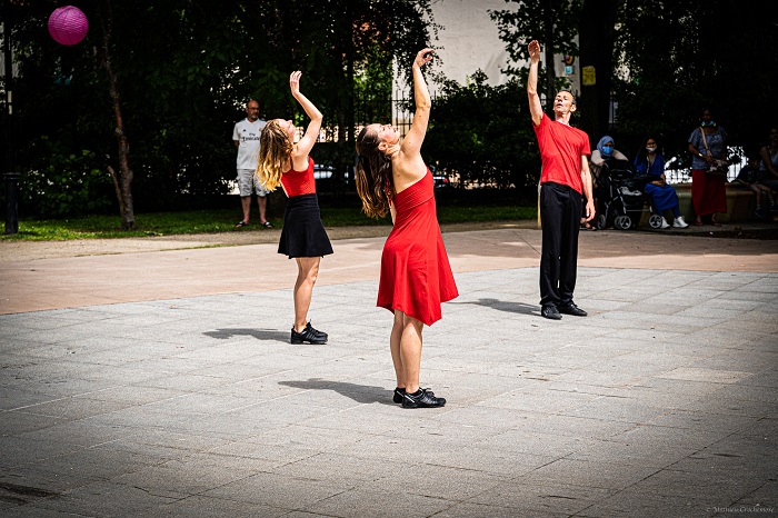 Trois danseurs en rouge et noir dansent devant l’arrêt de métro Fort d’Aubervilliers pendant l’AuberJazz Day