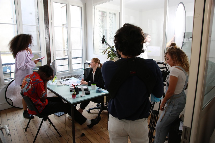 Scène de tournage dans un bureau avec environ cinq personnes 