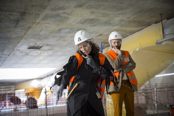 Deux comédiens en gilets de chantier orange sous le puits d’un chantier du Grand Paris Express dans le cadre du spectacle théâtralisé « Visite insolite de chantier » par la Compagnie Méliadès dans le chantier de l’entonnement Salengro à Champigny-sur-Marne en 2021