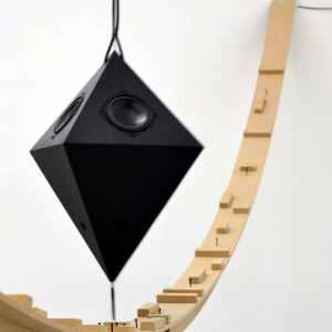 Arc en bois avec au-dessus une suspension en forme géométrique noire, installation issue de l’exposition collective « Hasard pendulaire » avec Mathias Isouard