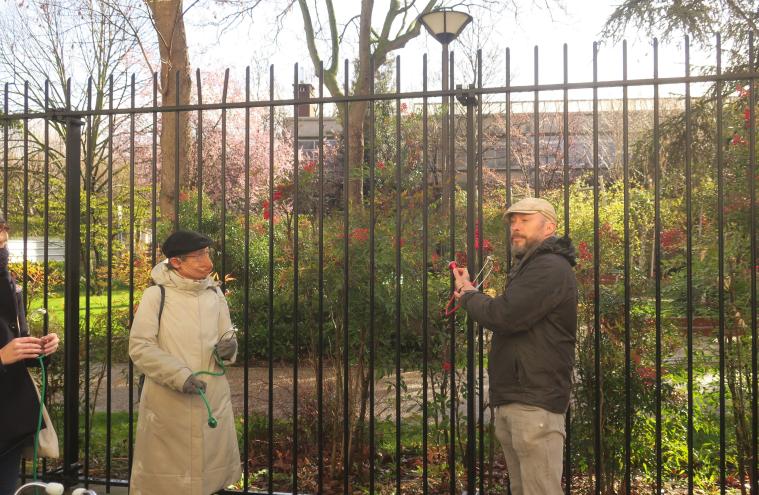 Une dizaine de personnes sont avec un stéthoscope le long de la barrière d’un parc, afin d’écouter les sons de la ville dans le cadre de la balade sonore aux abord des chantiers du Grand Paris Express d’Aubervilliers par la Compagnie Décor Sonore