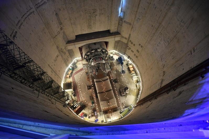 Vue en plongée sur le puits et la roue de coupe illuminée au fonds du puits, de nuit