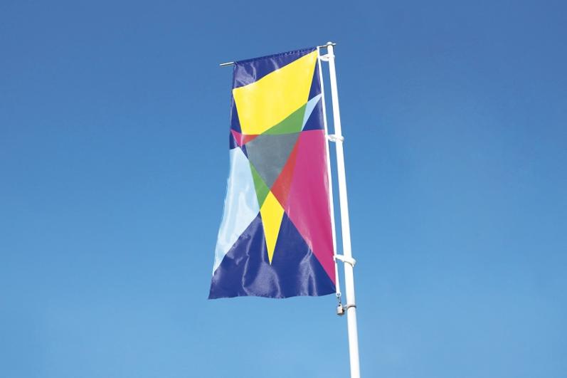 Drapeau avec motifs triangulaires jaunes, roses, bleux, dans le cadre du chantier du partagé « Agrafmobile » par Malte Martin à La Courneuve en 2018