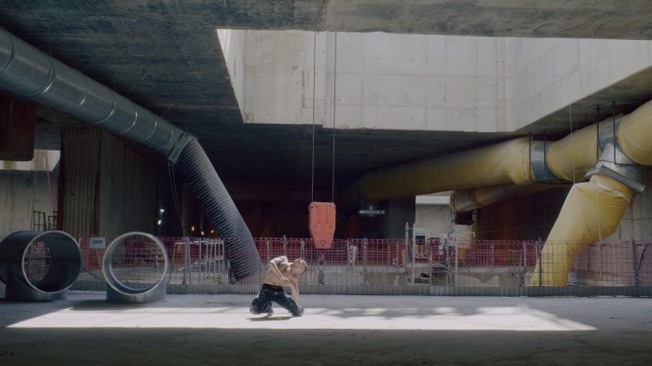 Le danseur Benjamin Bertrand torse nu en position allongée, en performance dans le chantier de l’ouvrage Salengro à Champigny
