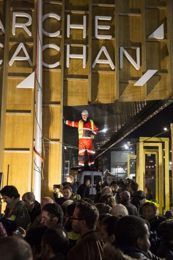 Le public devant un portique en bois sur lequel est écrit « Arcueil Cachan »