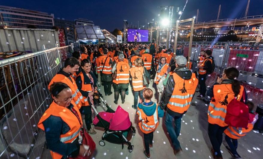 Public en gilets de chantier orange la nuit sur le chantier du puits Mandela à Saint-Denis