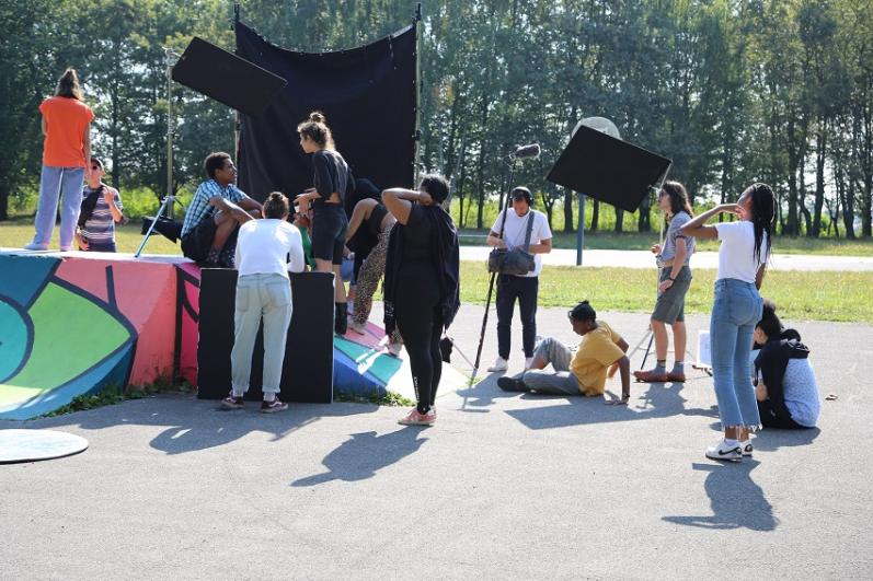 Scène de tournage en espace public avec une dizaine de personnes