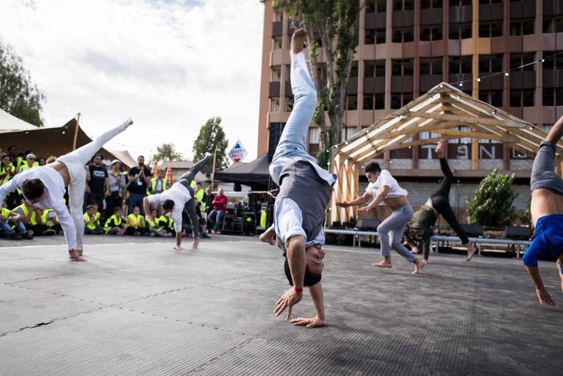 Performance du groupe acrobatique de Tanger lors du KM4 à La Courneuve, acrobates réalisant des figures avec en arrière-plan le public en gilets jaunes de chantier, de jour