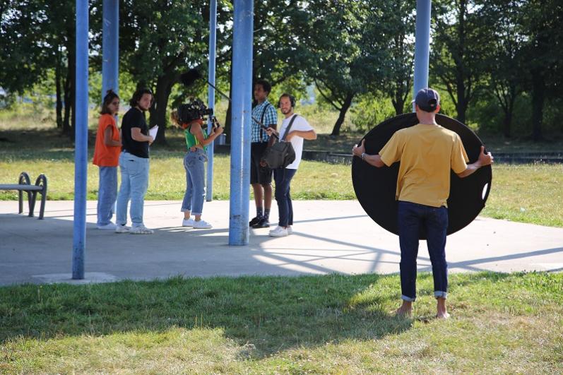 Scène de tournage en espace public avec une dizaine de personnes