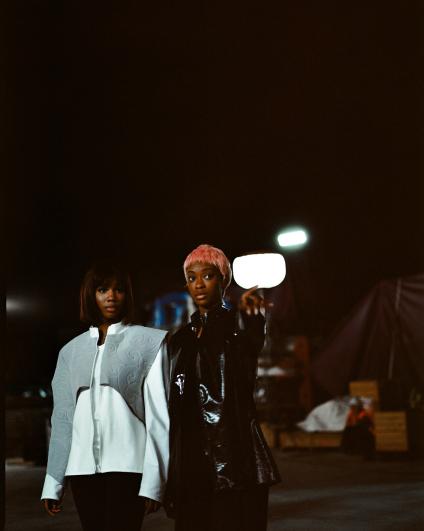 Photo de deux des participantes aux ateliers avec sa création de vêtements, tournage sur le chantier de la future gare d’Aulnay