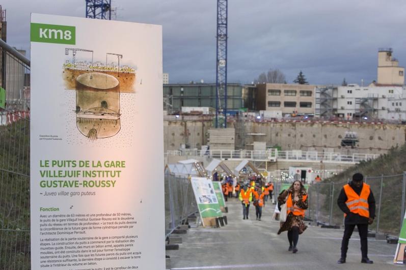 Panneau illustré de présentation du puits de la gare dans une allée du chantier de la future gare de Villejuif Institut Gustave-Roussy