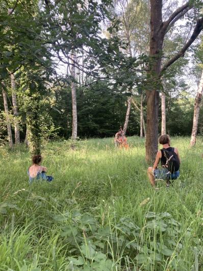 personnes accroupies dans l'herbe derrière des arbres